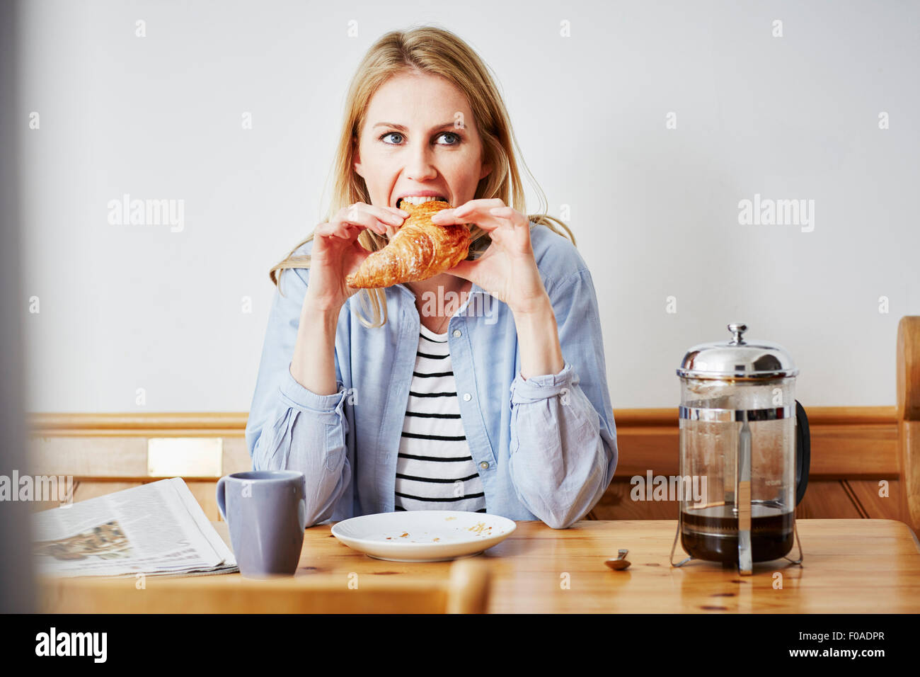 Metà donna adulta mangiare croissant Foto Stock