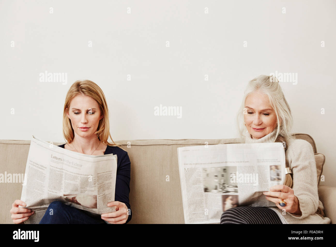 Senior e metà donne adulte leggendo quotidiani Foto Stock