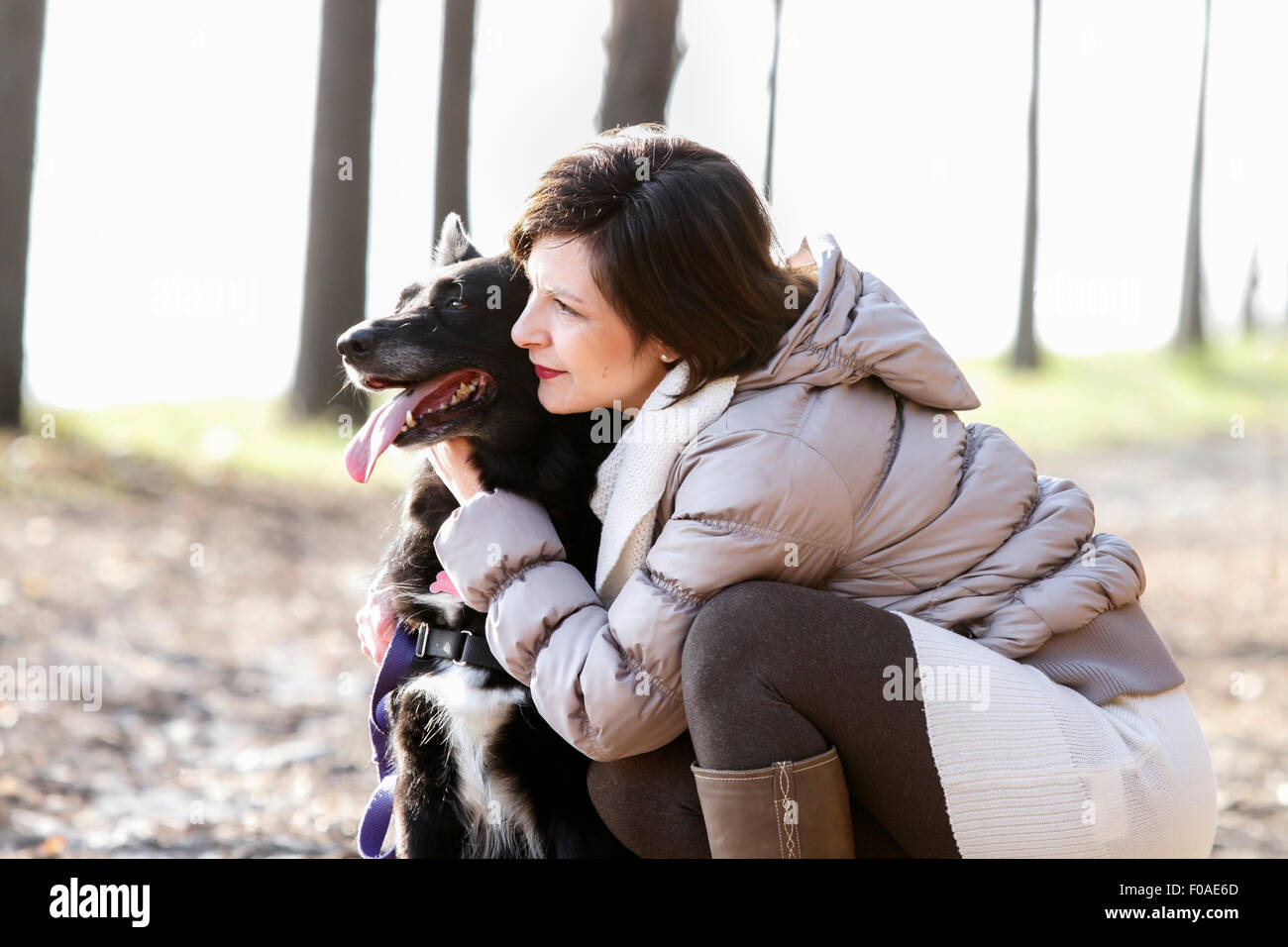 Metà donna adulta accovacciato con il suo cane sul percorso di sporcizia Foto Stock