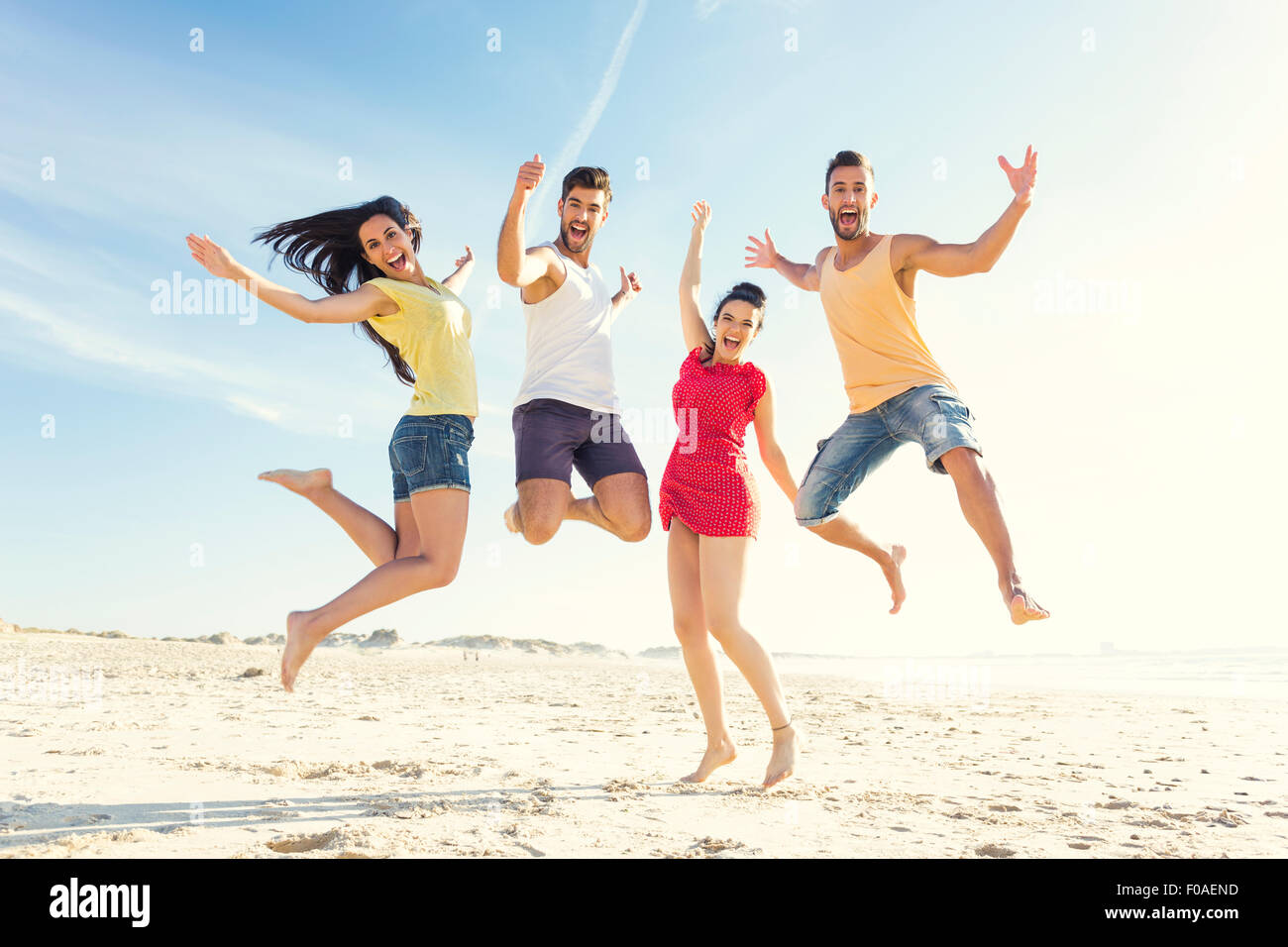 Gruppo di amici facendo un salto insieme in spiaggia Foto Stock