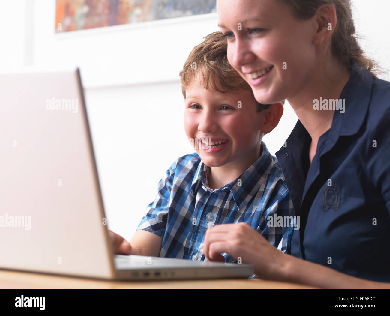 Giovane donna e figlio utilizzando portatile a casa Foto Stock