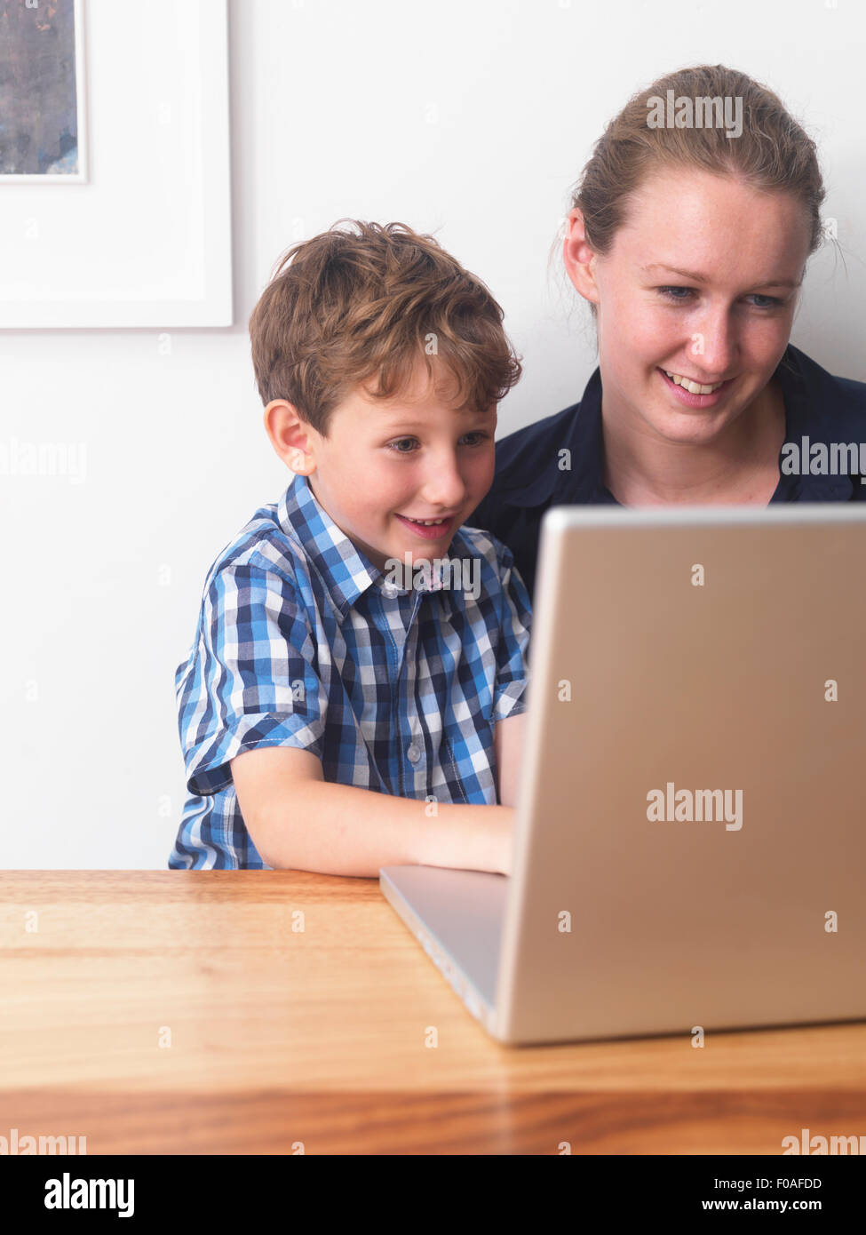 Giovane donna e figlio utilizzando laptop insieme a casa Foto Stock