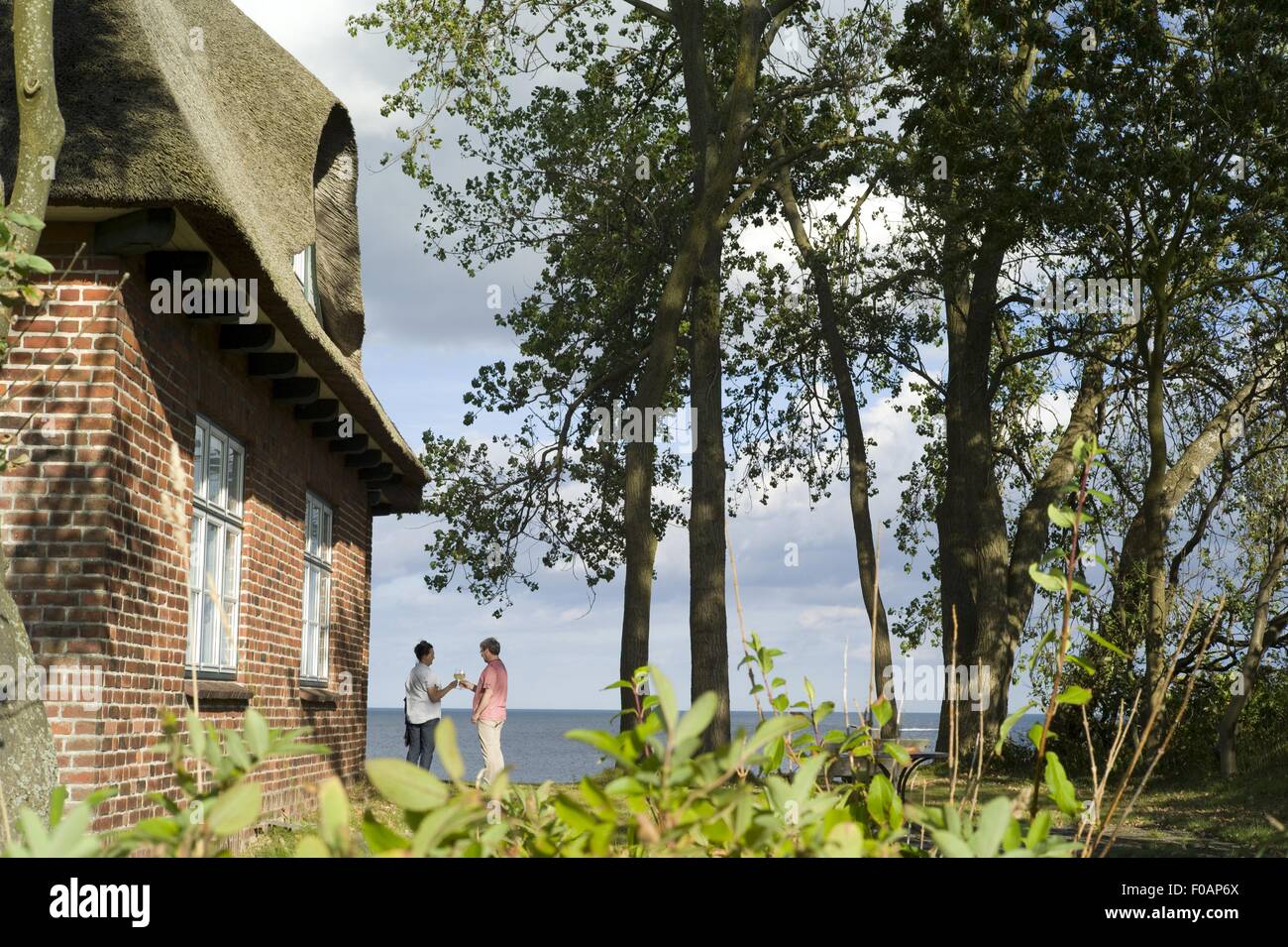 Persone in piedi vicino al cottage con il tetto di paglia, Dahme, Schleswig Holstein, Germania Foto Stock