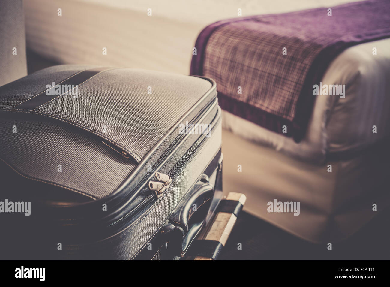 Camera in hotel con una valigia sul posto per i bagagli e il letto. Filtrata shot Foto Stock
