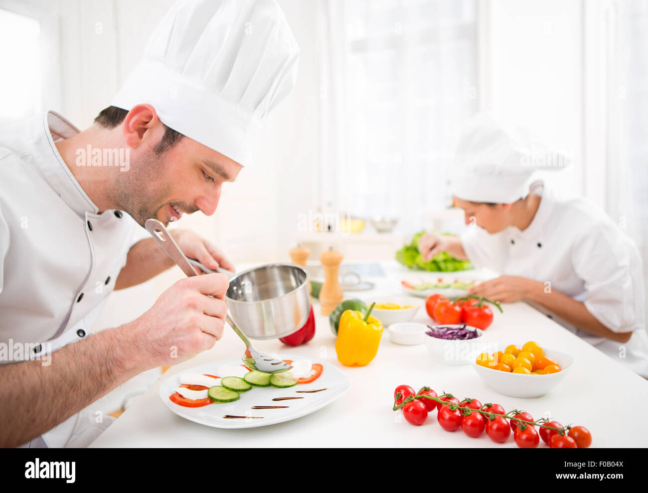 Vista di un giovane attraente chef professionale per la cottura nella sua cucina Foto Stock