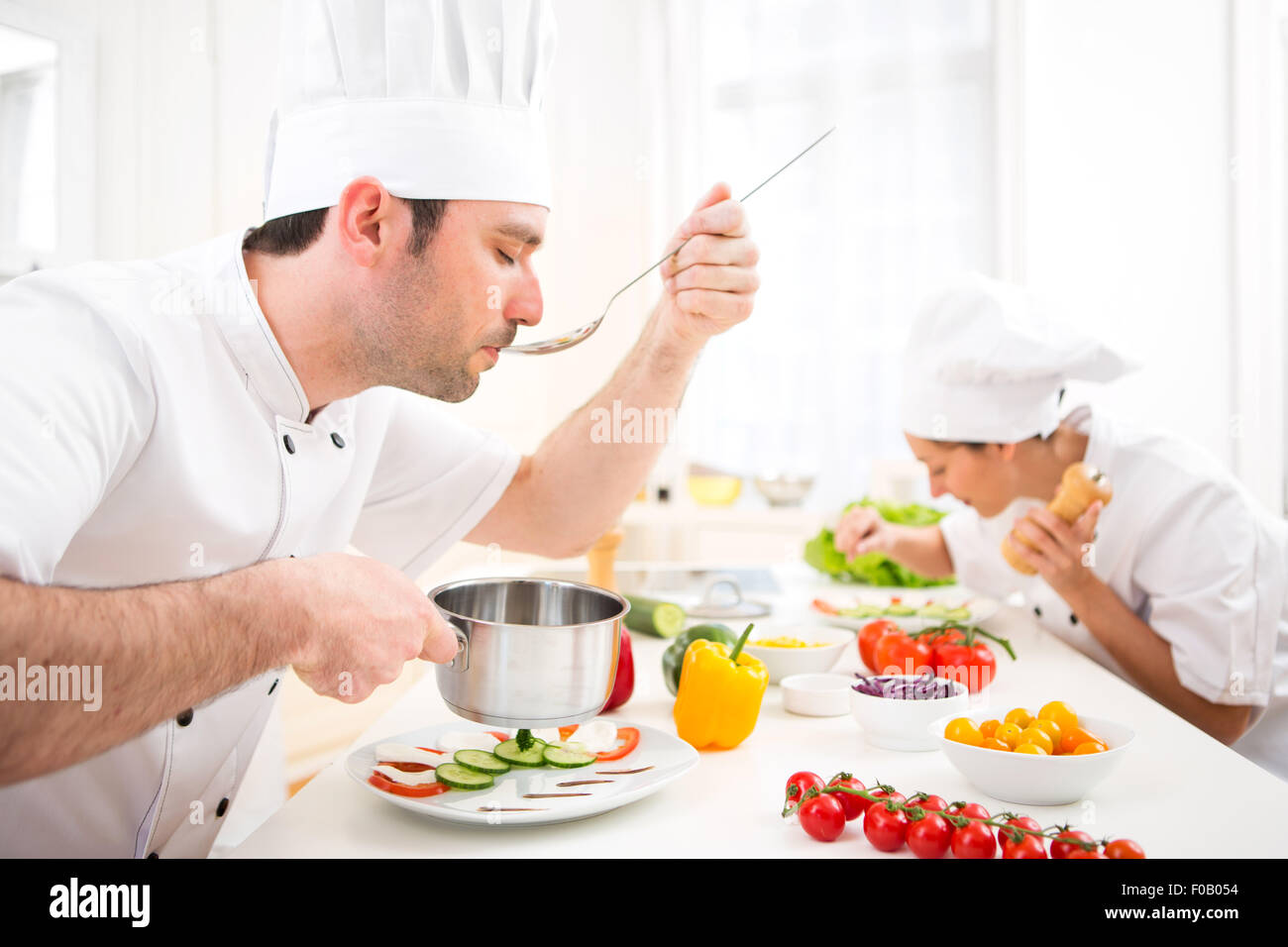 Vista di un giovane attraente chef professionale salsa di degustazione Foto Stock