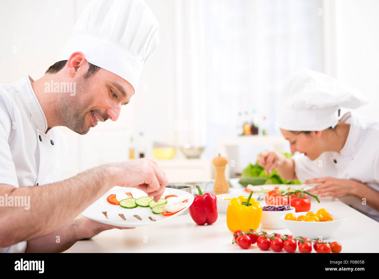 Vista di un giovane attraente chef professionale per la cottura nella sua cucina Foto Stock