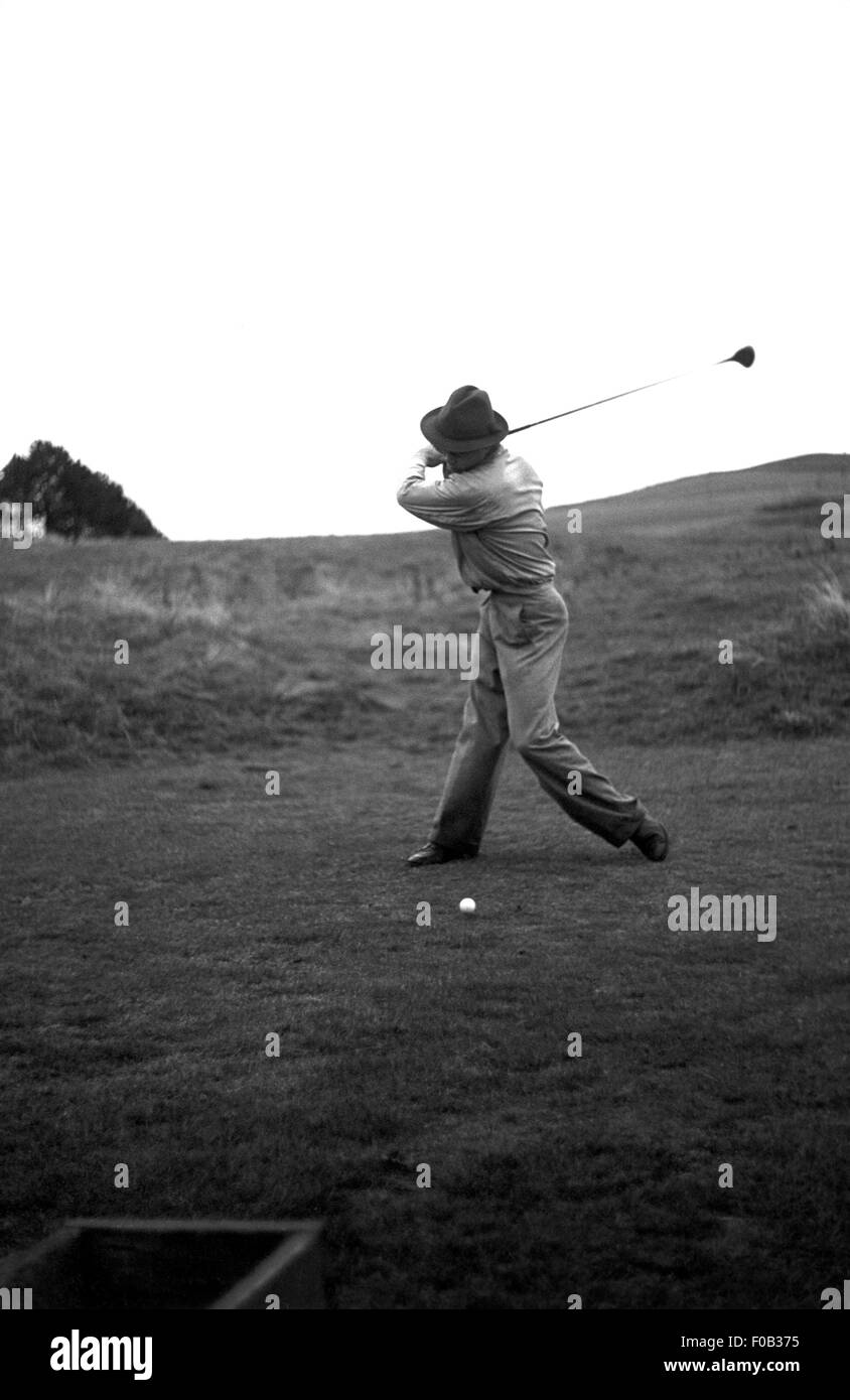 Uomo a metà swing con un club di golf. Foto Stock