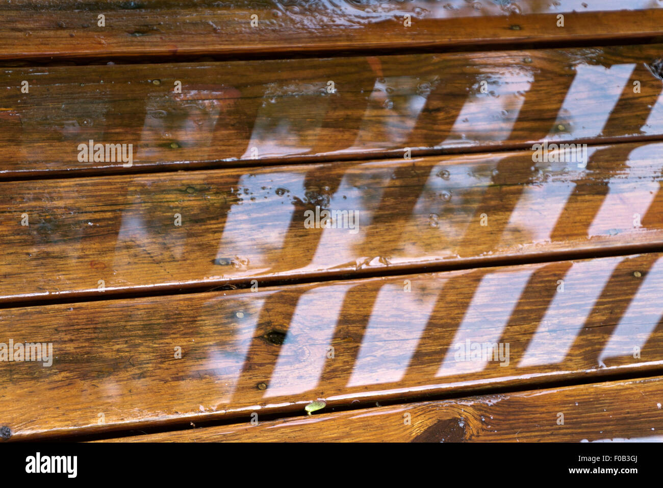 Close up sul bagnato e stagionato di pannelli di legno di un terrazzo all'aperto dopo un acquazzone estivo Foto Stock