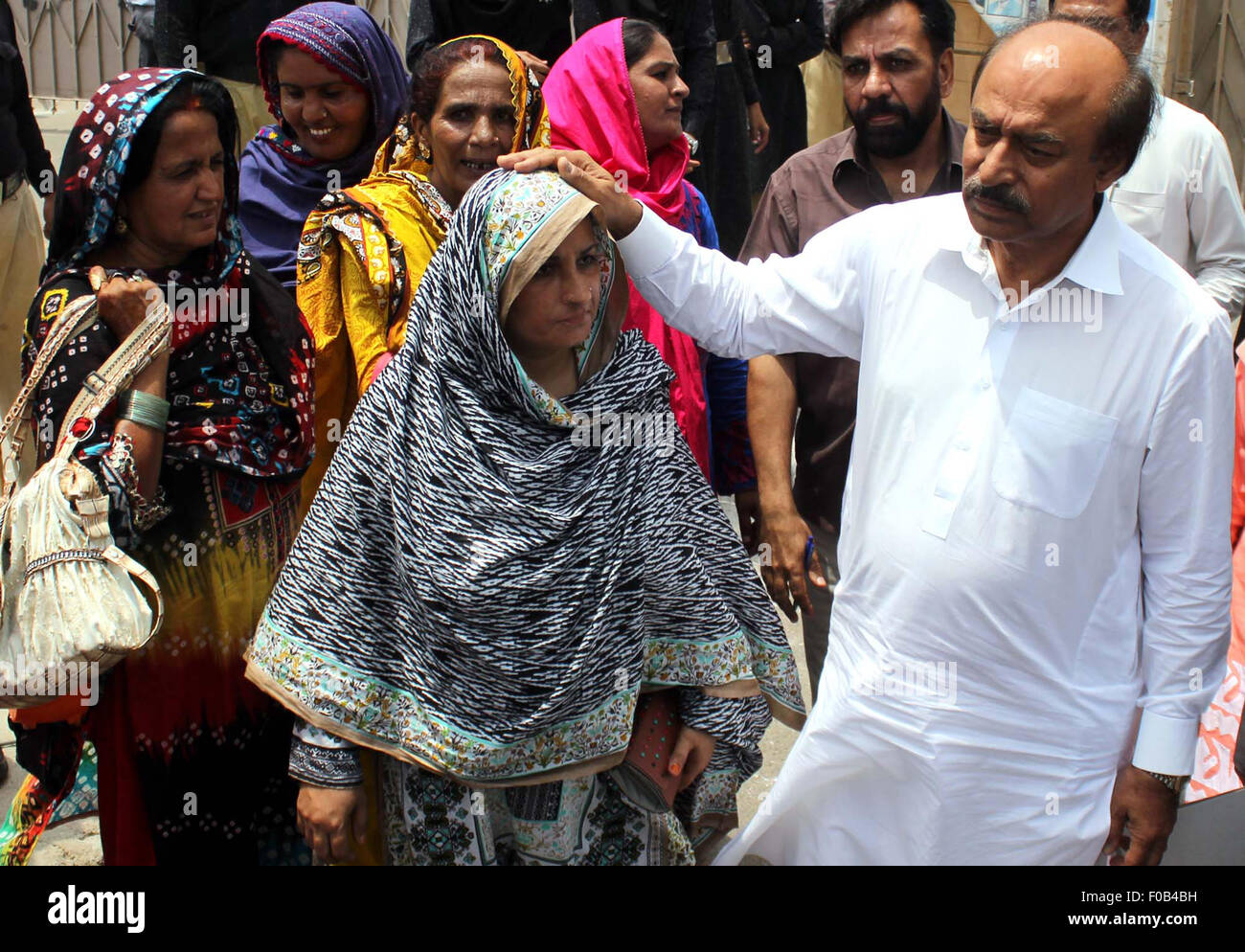 Uomo politico Senior, leader del Partito dei popoli Nisar Khoro consolante Lady lavoratori della sanità che protestavano contro il mancato pagamento dei loro stipendi, al di fuori del gruppo di Sindh in Karachi il Martedì, Agosto 11, 2015. Foto Stock