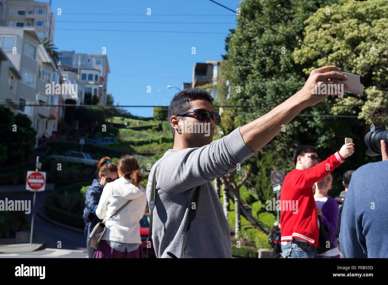 Un turista pone per un selfie presi con il suo telefono cellulare nella parte anteriore del Lombard Street a San Francisco, California, Stati Uniti d'America Foto Stock