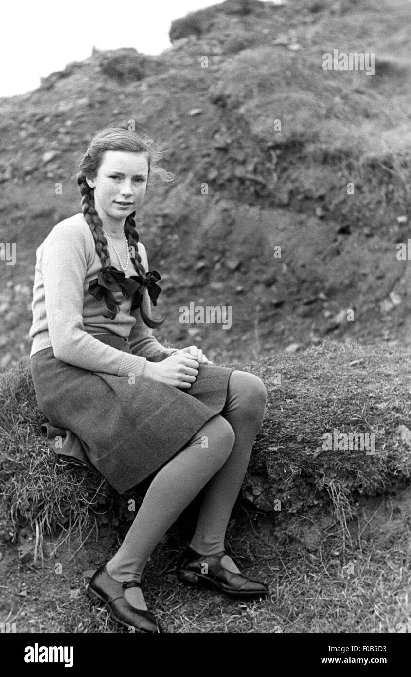 Una giovane donna seduta in campagna Foto Stock