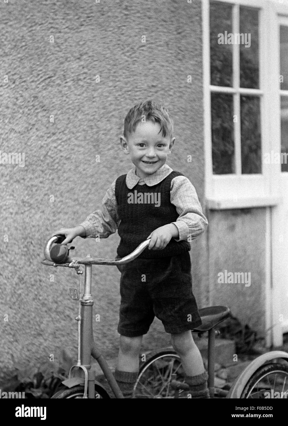 Un ragazzo su un triciclo Foto Stock