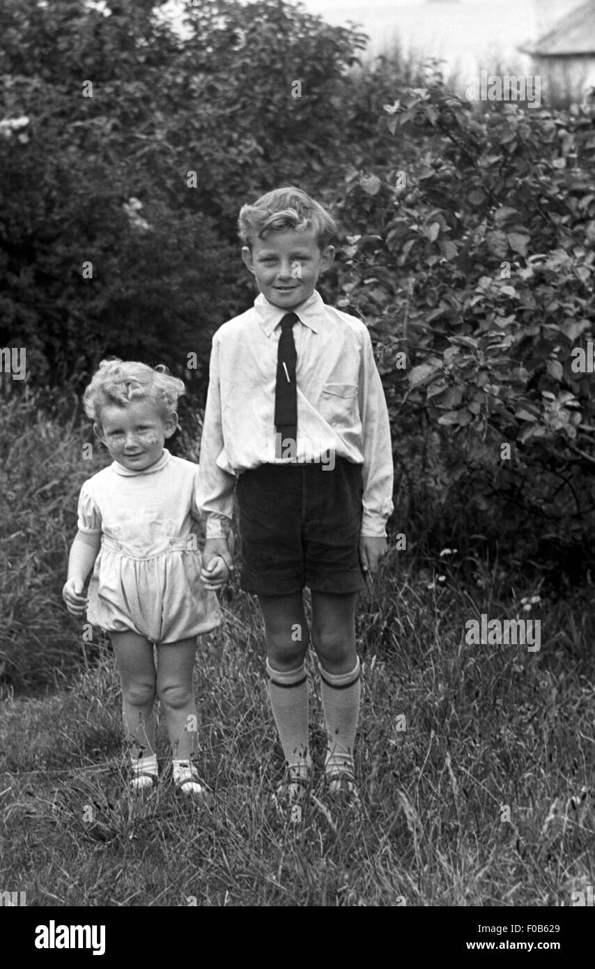 Un giovane ragazzo tenendo per mano del suo fratello più giovane Foto Stock