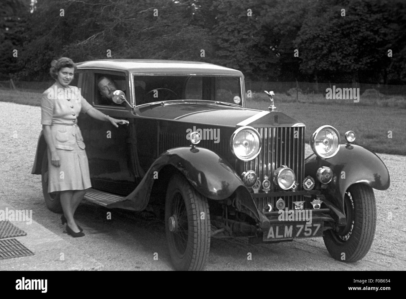 Una donna in piedi accanto a una Rolls Royce auto, con un uomo nel sedile del conducente. Foto Stock