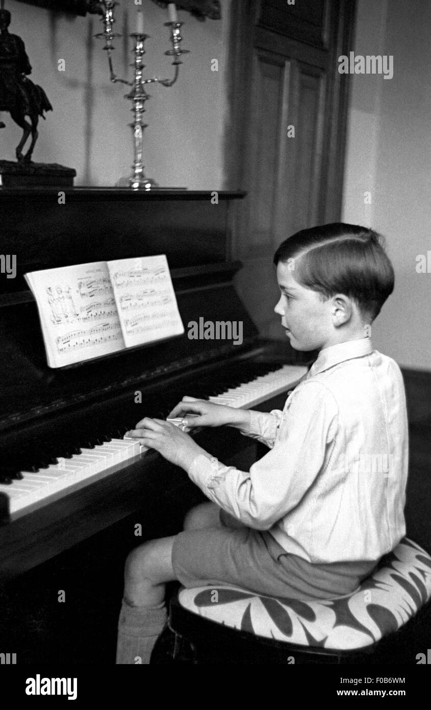 Un giovane ragazzo lettura musica e suonare il pianoforte. Foto Stock