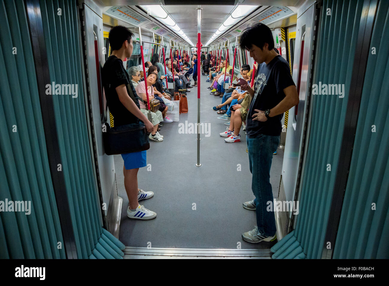 I passeggeri a bordo di una vettura della metropolitana di Hong Kong, Cina Foto Stock