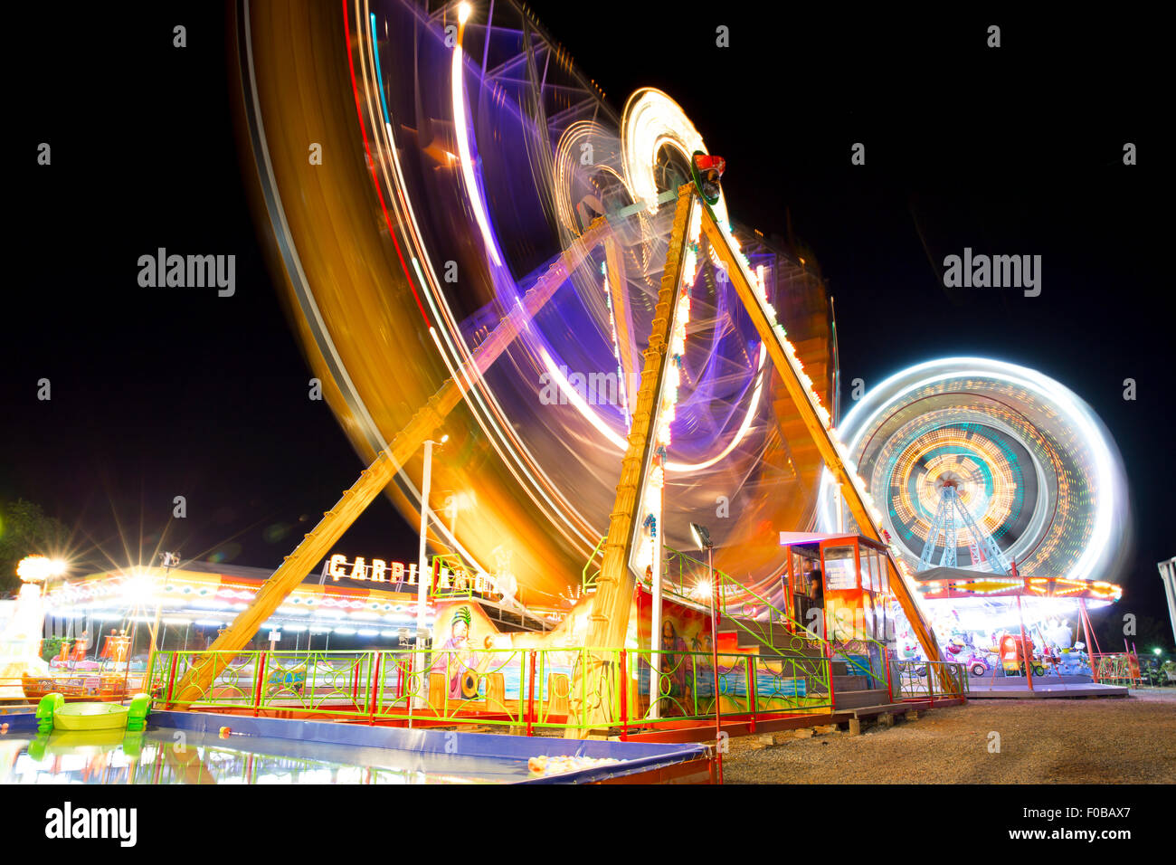 Coloratissimo carnevale ruota panoramica Ferris e gondola la filatura in movimento sfocati di notte in un parco di divertimenti Foto Stock
