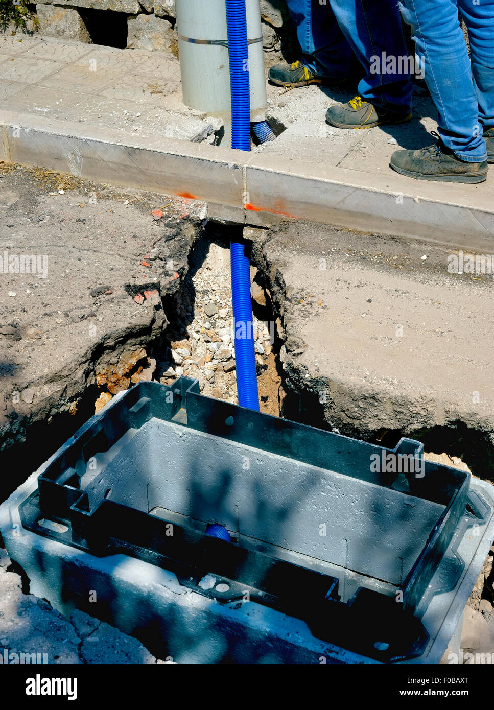 Cavi a fibra ottica sepolto in un micro trench da un lavoratore Foto Stock