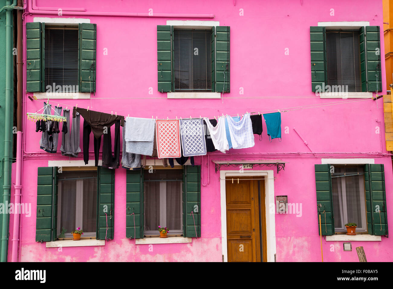 Tradizionale casa colorata in isola di Burano con biancheria in asciugatura nel mezzo del cortile tra case colorate vetro Foto Stock
