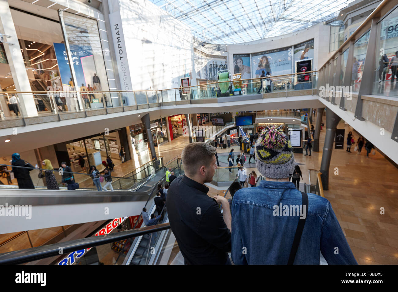 Persone di andare giù su scale mobili in Birmingham Bullring Shopping Centre Regno Unito Foto Stock