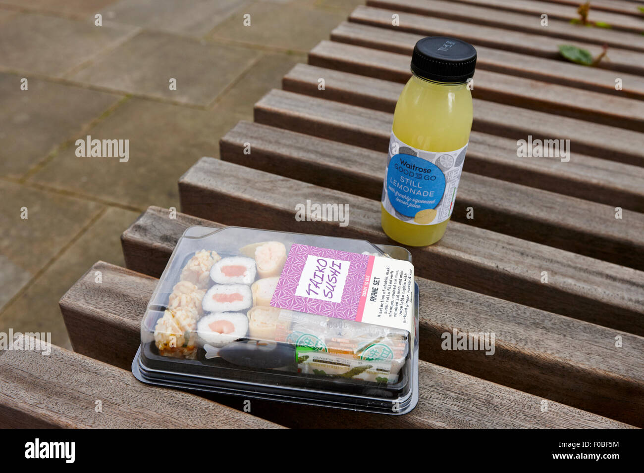 Il sushi e limonata ancora il pranzo per lavoratore di ufficio su una panchina nel parco Birmingham REGNO UNITO Foto Stock