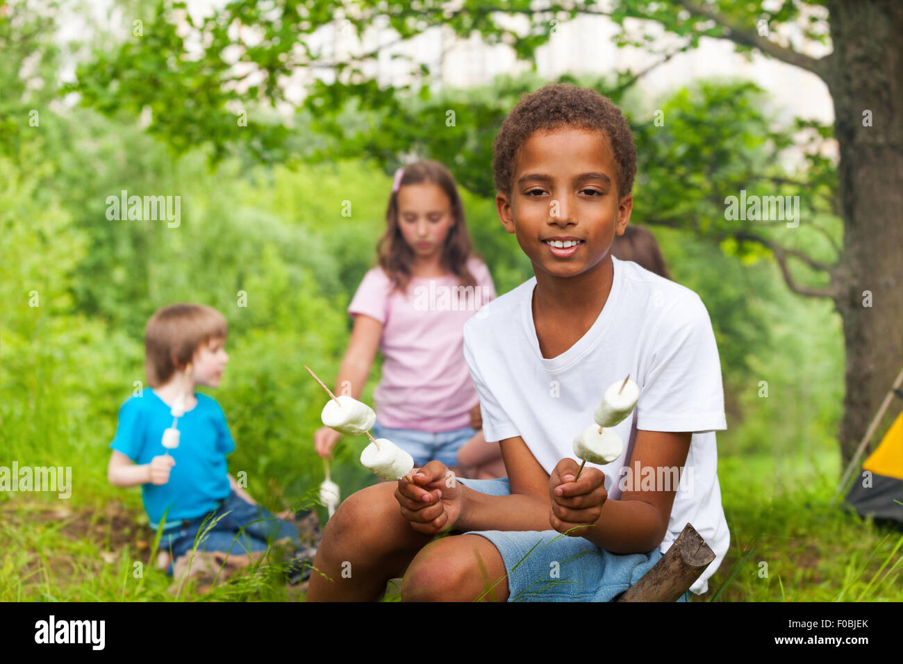 Carino il ragazzo africano con marshmallows durante il campeggio Foto Stock