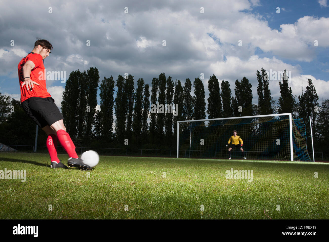 Lunghezza completa di giocatore di calcio calci palla al traguardo Foto Stock