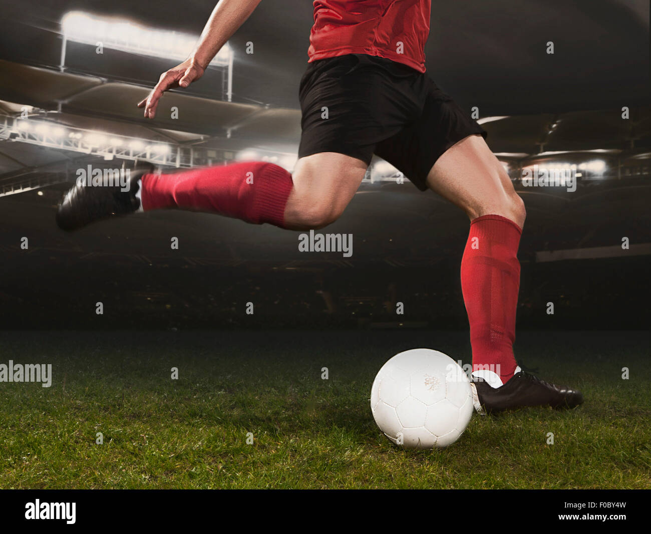 Sezione bassa del giovane giocatore di calcio calci palla sul campo Foto Stock