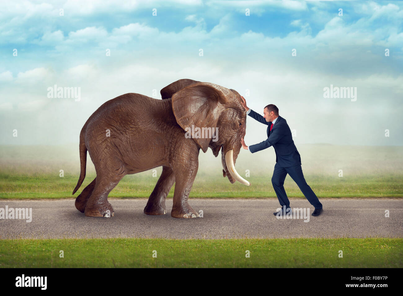 Sfida aziendale spingendo contro ostacolo elefante contest di forza Foto Stock