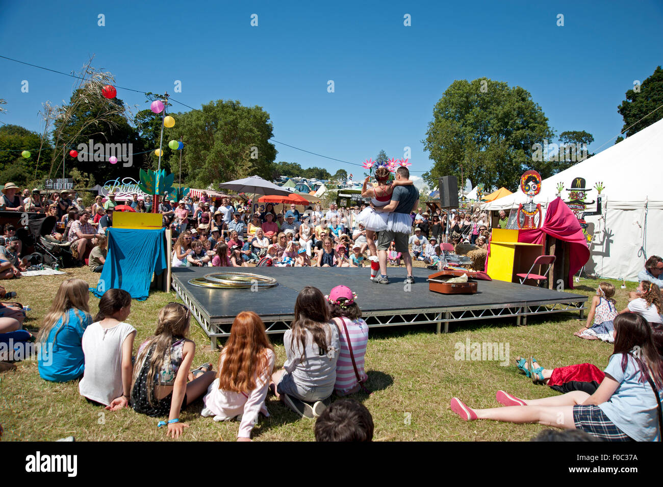 Le famiglie di guardare un atto acrobatico in estate sole a chioschi e tabelloni elettronici al porto Eliot Festival Cornovaglia Foto Stock