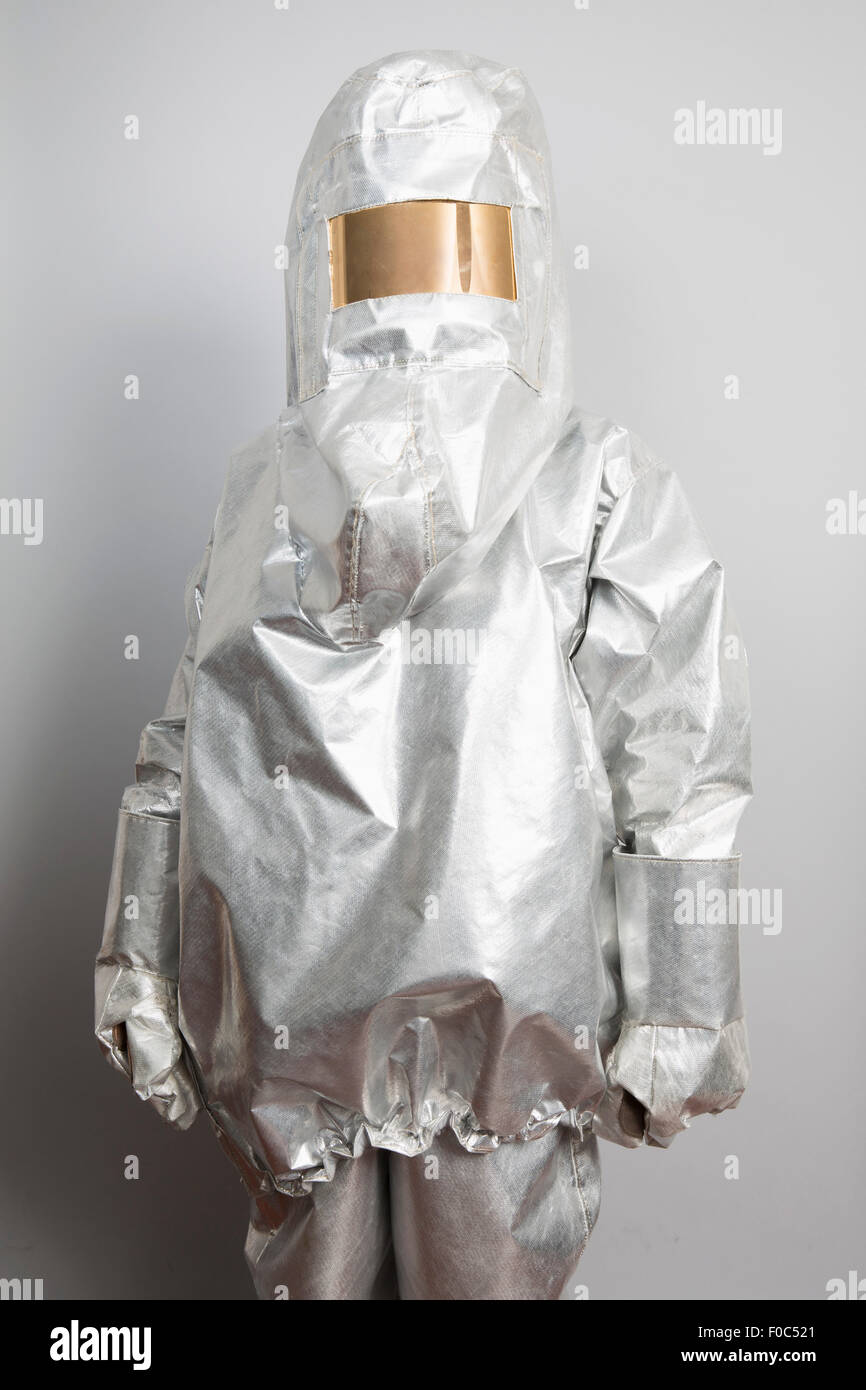 Una persona in un radioattivo tuta di protezione in piedi contro uno sfondo grigio Foto Stock