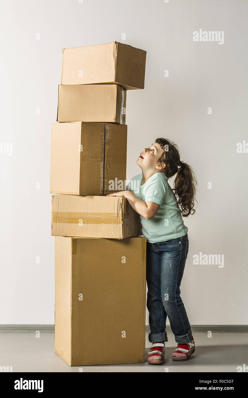 Per tutta la lunghezza della ragazza di stack di bilanciamento scatole in casa Foto Stock