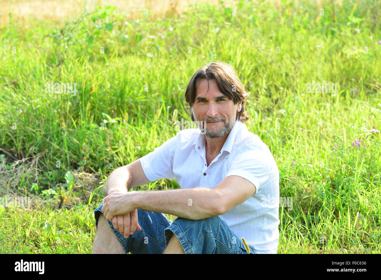 Un uomo si siede nel prato in estate Foto Stock