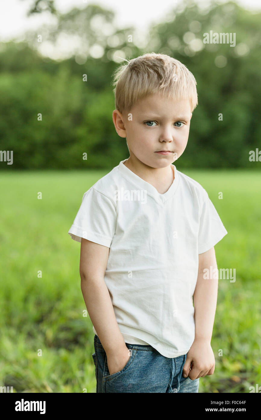 Ritratto di ragazzo carino in piedi con la mano in tasca sul campo Foto Stock
