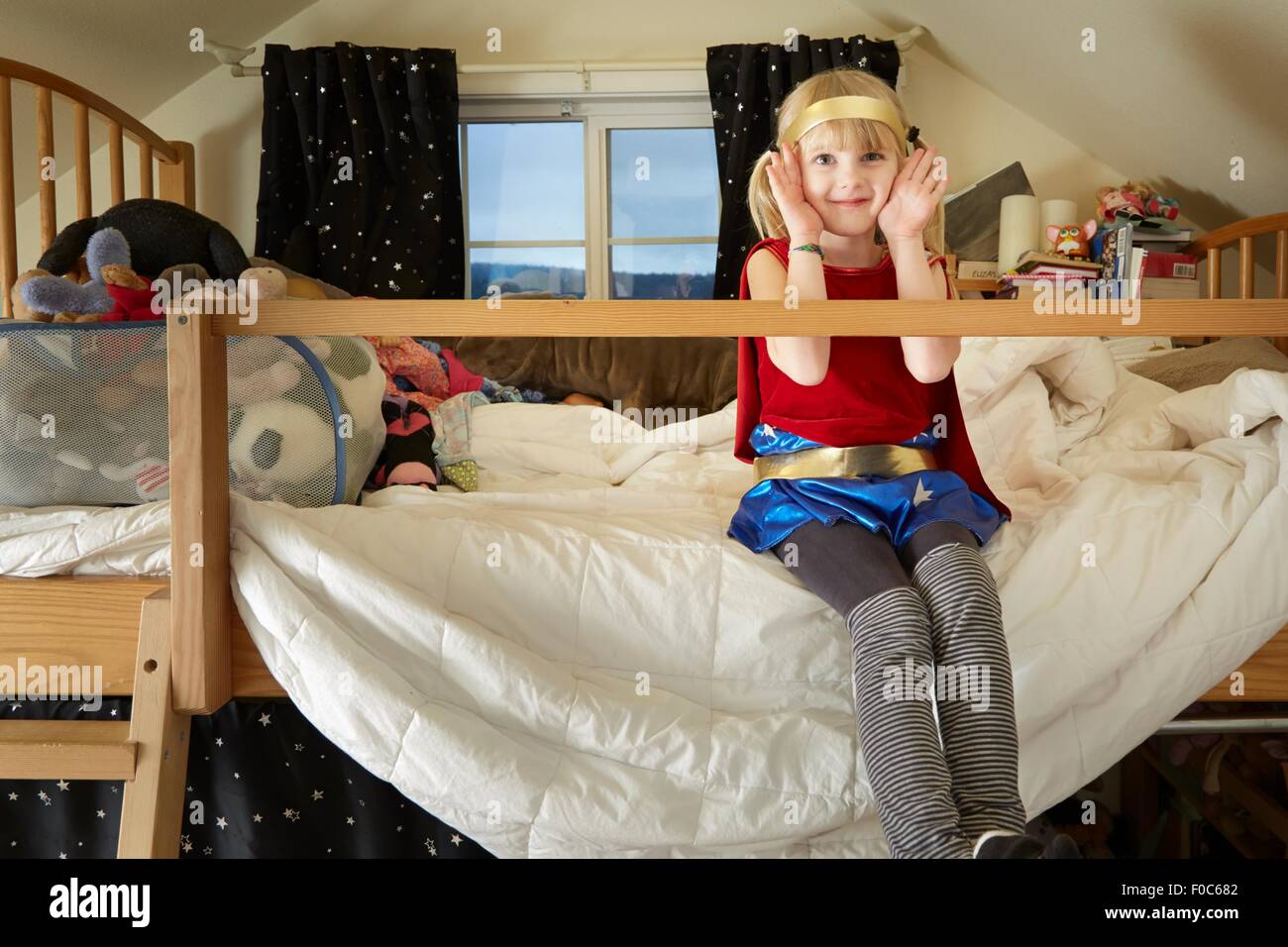Ritratto di giovane ragazza seduta sul letto, indossando abiti fantasiosi costumi Foto Stock