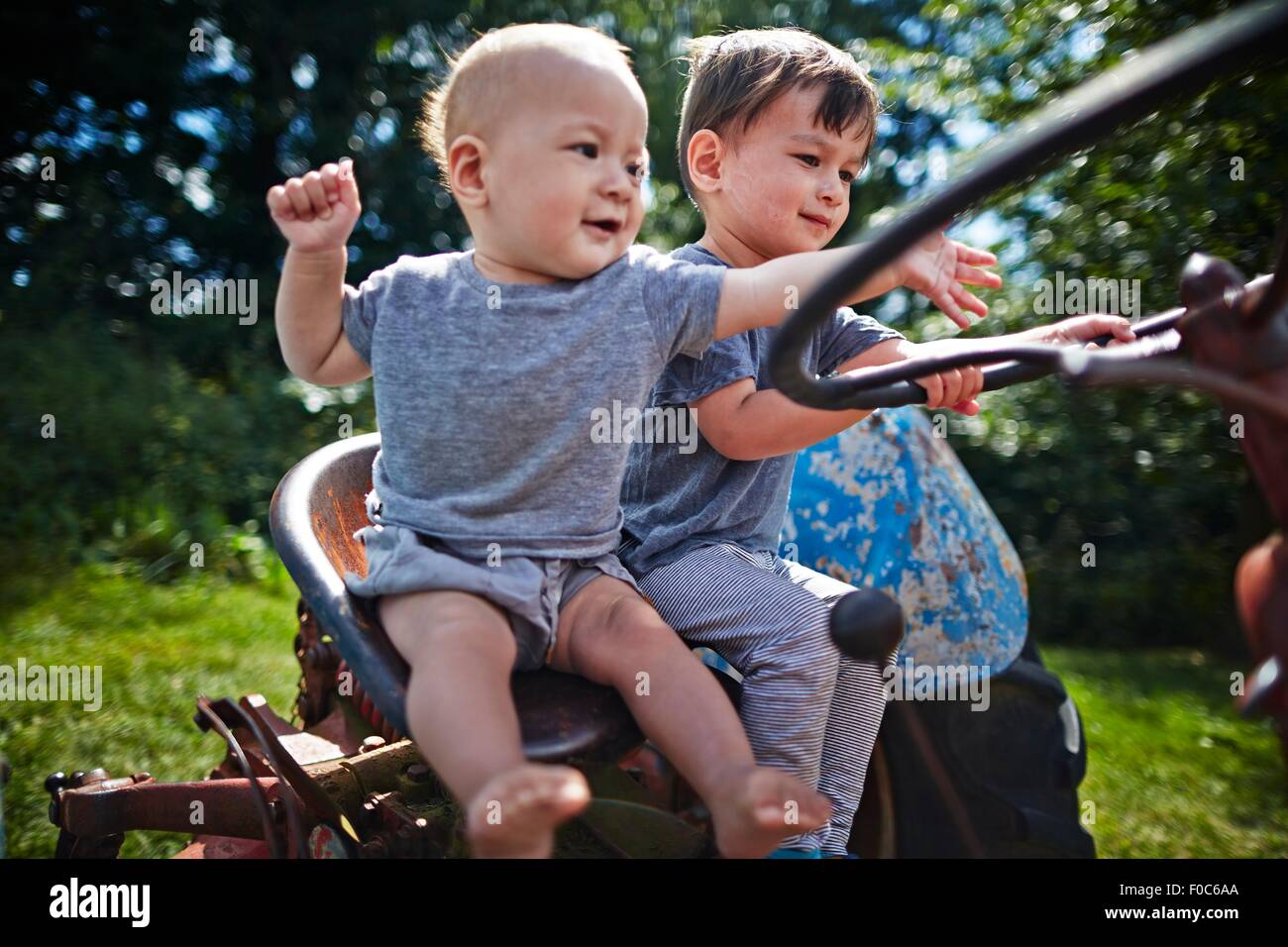 Baby boy e ragazzo giocando sul vecchio trattore Foto Stock