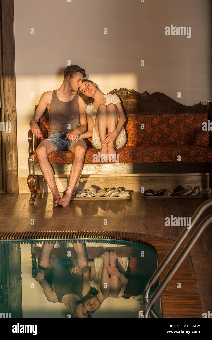 Amorevole coppia giovane seduto sul divano da piscina Foto Stock