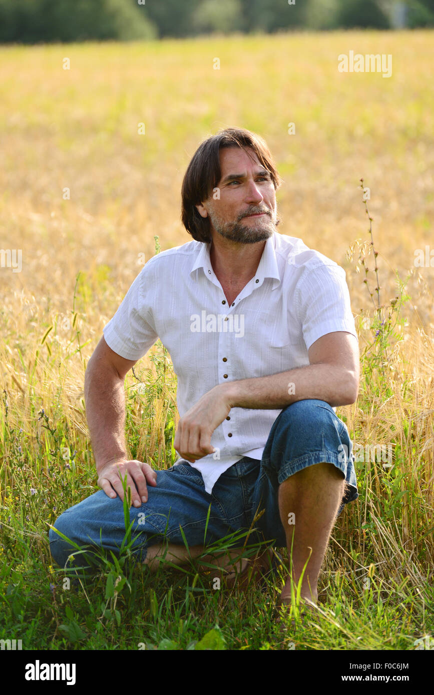 Un uomo si siede vicino a un campo di grano Foto Stock