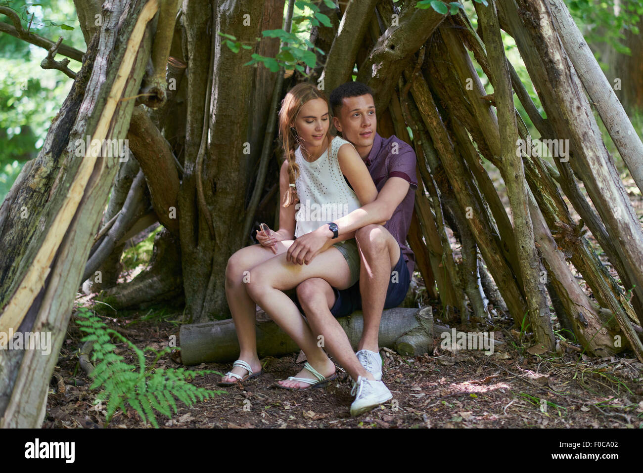 Giovane donna seduta sull uomo di giro sotto log in posizione di parcheggio Foto Stock