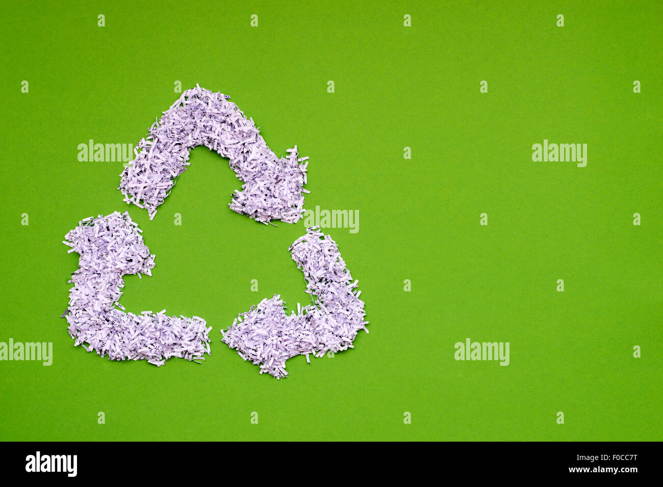 Simbolo di riciclaggio realizzato dal mucchio di shredded carta bianca su sfondo verde Foto Stock