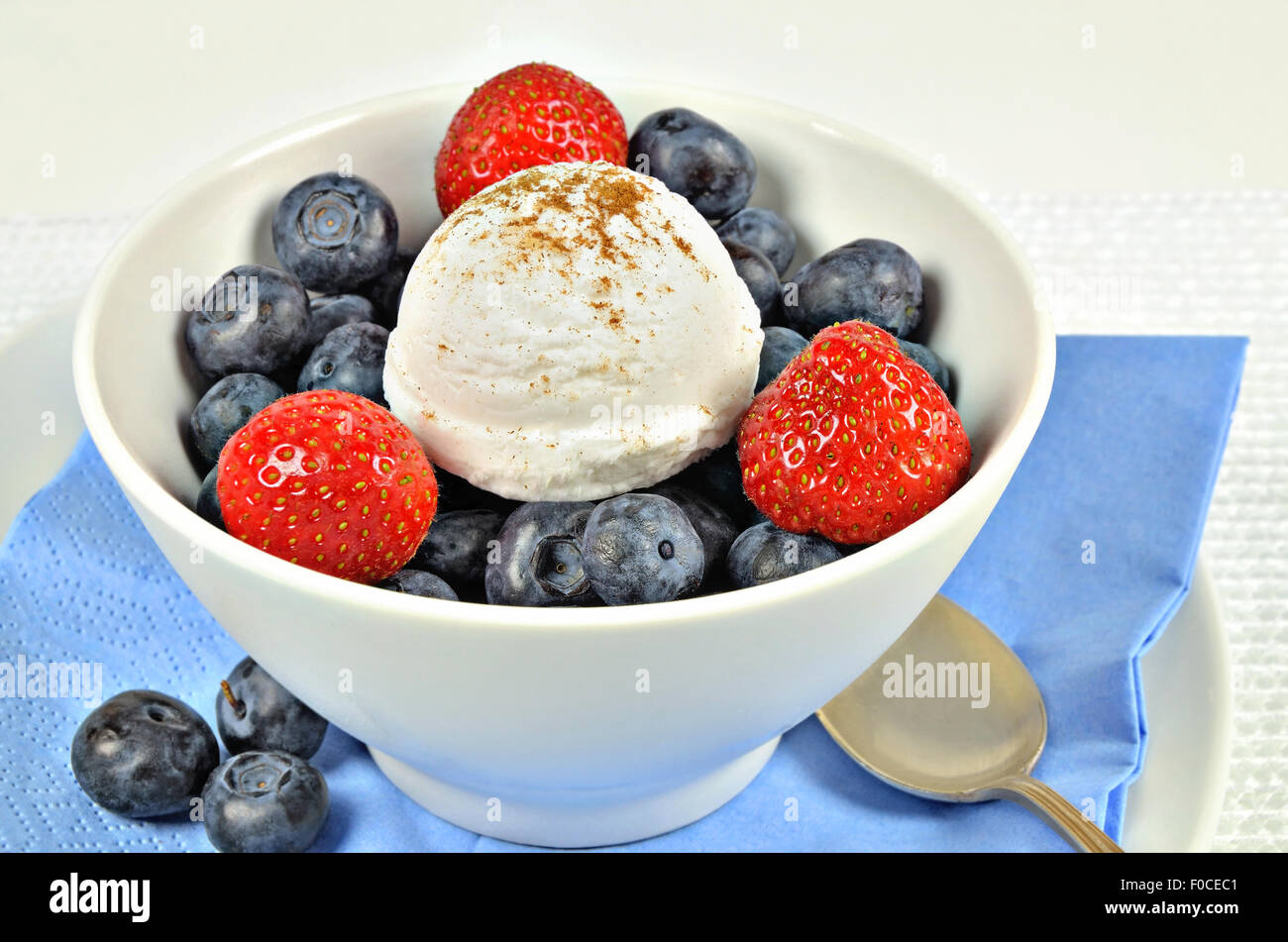 Chiudere fino a un bianco ciotola con gelato alla vaniglia e fragole e mirtilli, macro, full frame, orizzontale Foto Stock