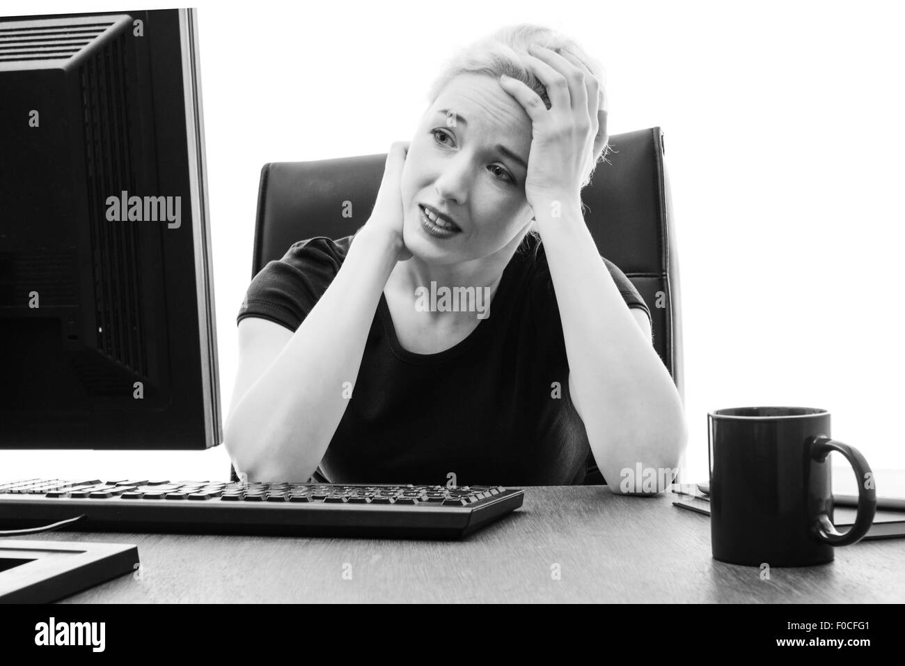 Donna seduta alla sua scrivania con la sua testa nelle sue mani ha sottolineato Foto Stock