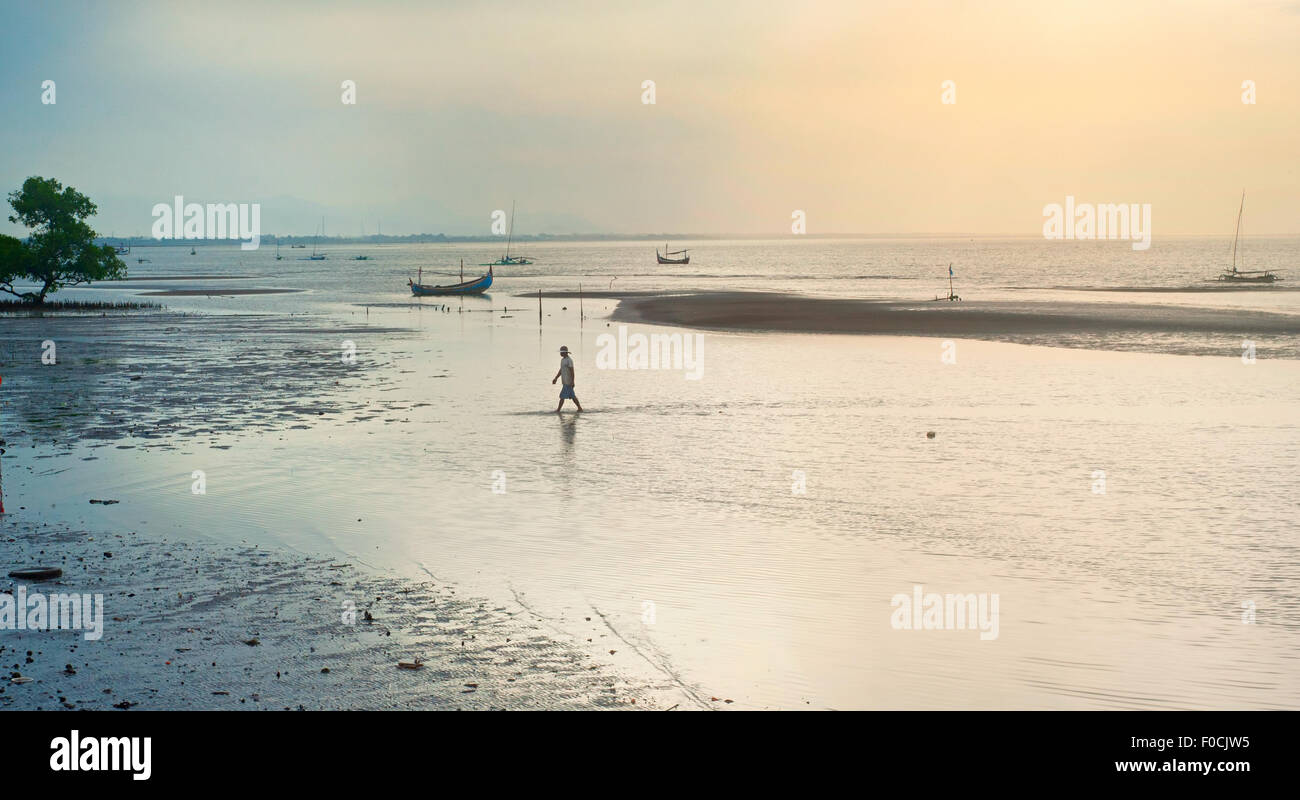 Pescatore di camminare sulla spiaggia al tramonto. Isola di Giava, in Indonesia Foto Stock