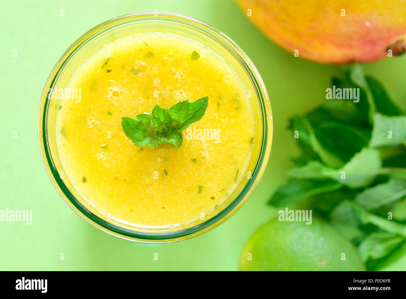 Il raffreddamento di Mango frullato di menta, bevanda estiva sul tavolo verde, giallo frullato tropicale fatta con mango, menta e il succo di lime. Foto Stock