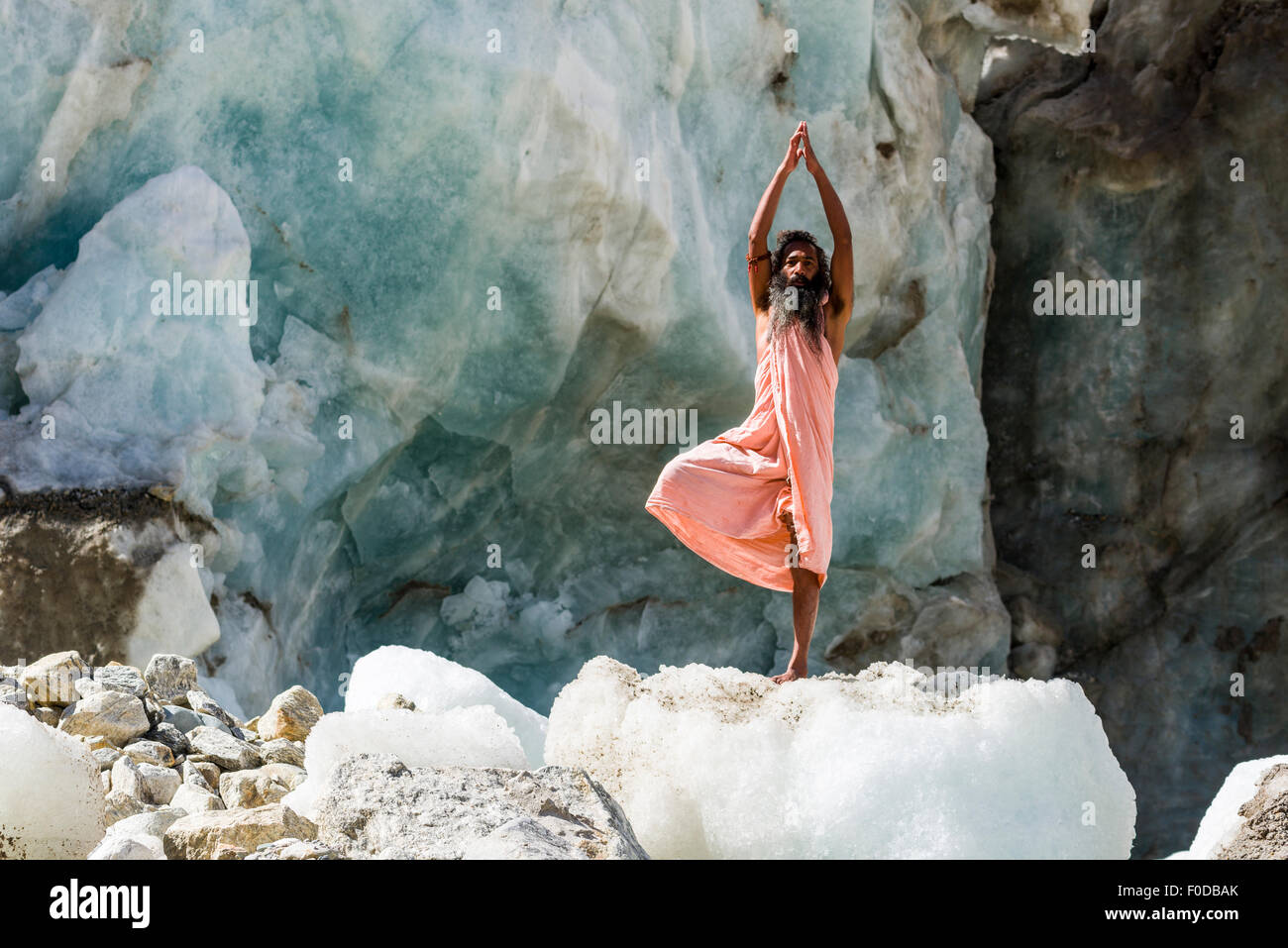 Un Sadhu, uomo santo, è in piedi in posa ad albero, vrikshasana su un blocco di ghiaccio a Gaumukh, la fonte principale del Sacro Gange Foto Stock