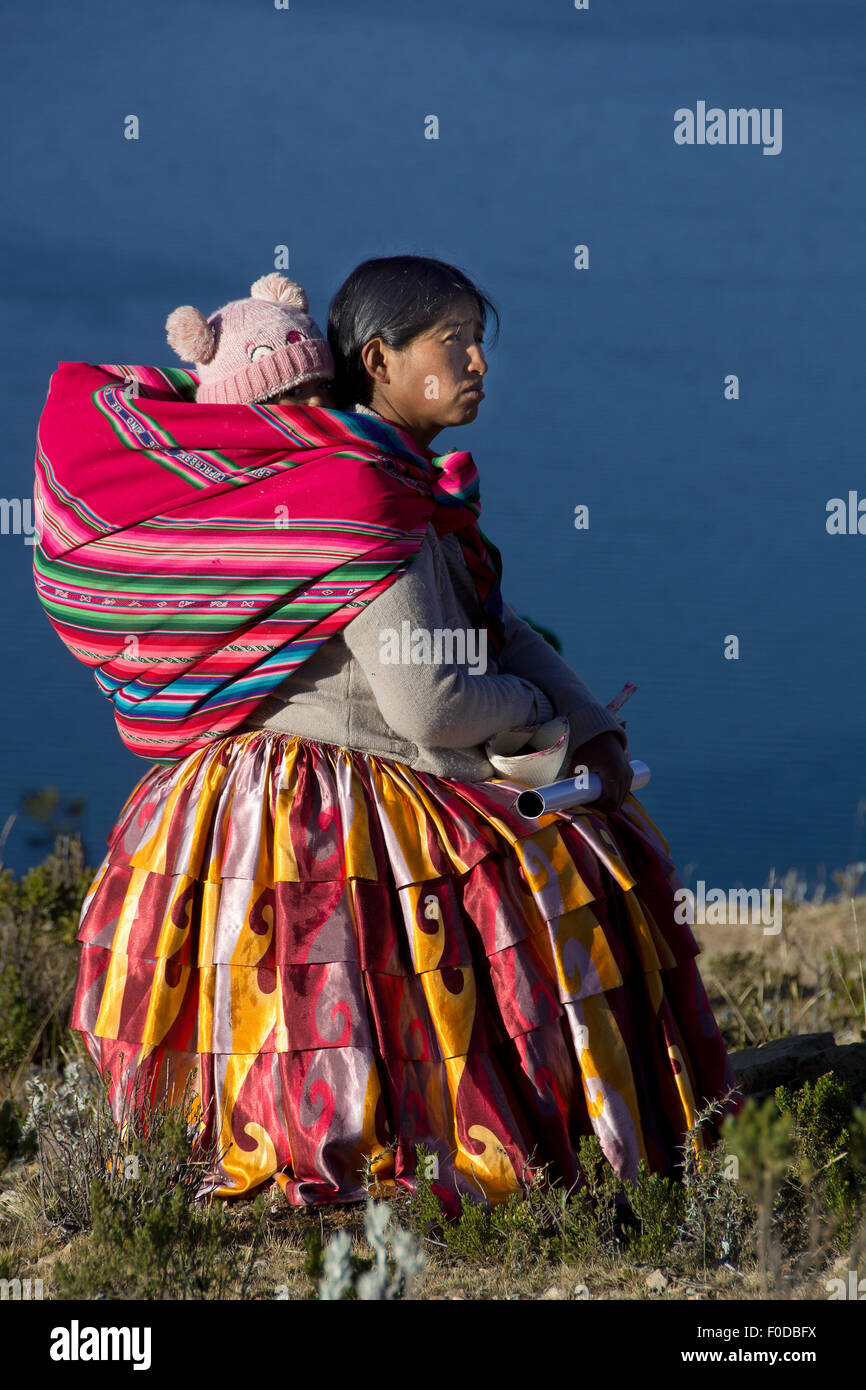Indio una donna con un bambino sulla schiena, abbigliamento tradizionale, nella parte anteriore del lago Titicaca, il lago Titicaca, l' isola del sole Foto Stock