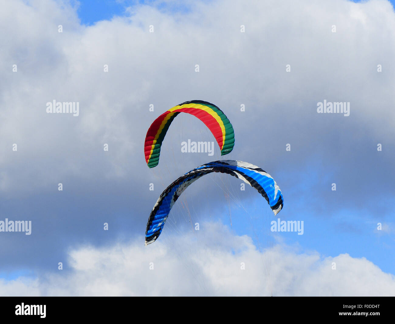 Paracadute colorato ed aquiloni battenti in blu cielo nuvoloso Foto Stock