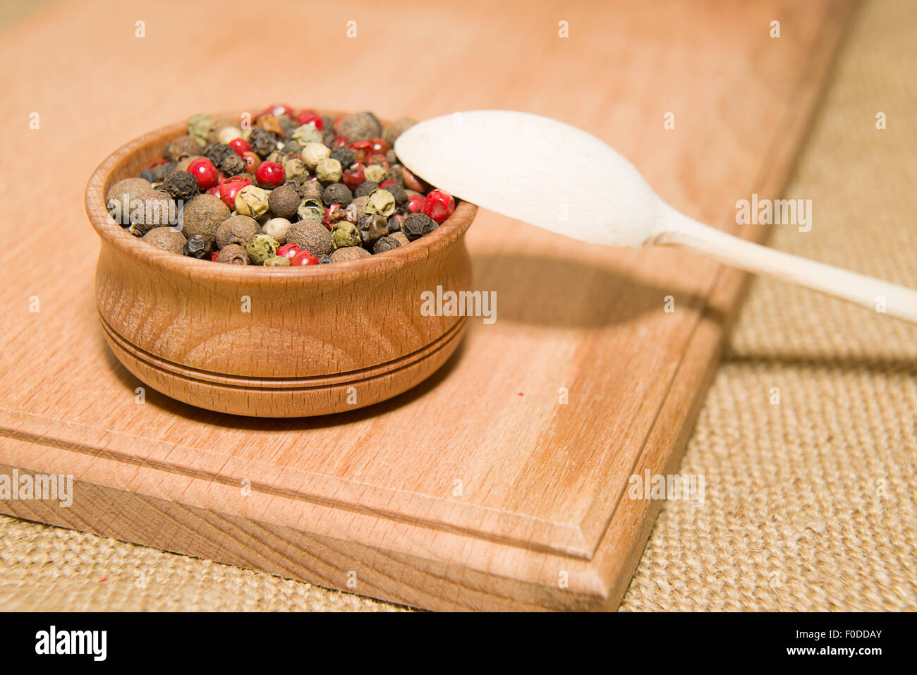 Una miscela di grani di pepe e il cucchiaio su una superficie in legno Foto Stock