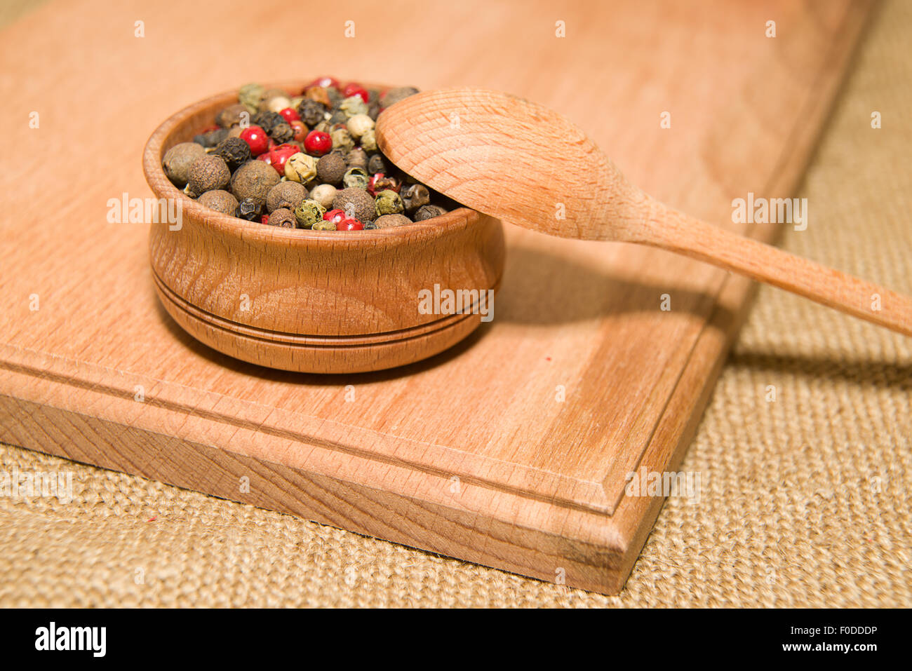 Una miscela di grani di pepe e il cucchiaio su una superficie in legno Foto Stock